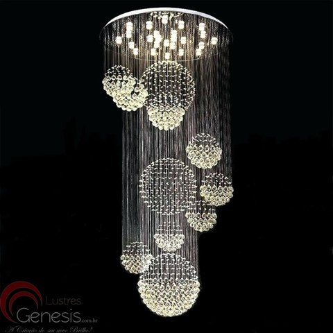 Lustre de cristal com esferas iluminadas suspensas em diferentes alturas.