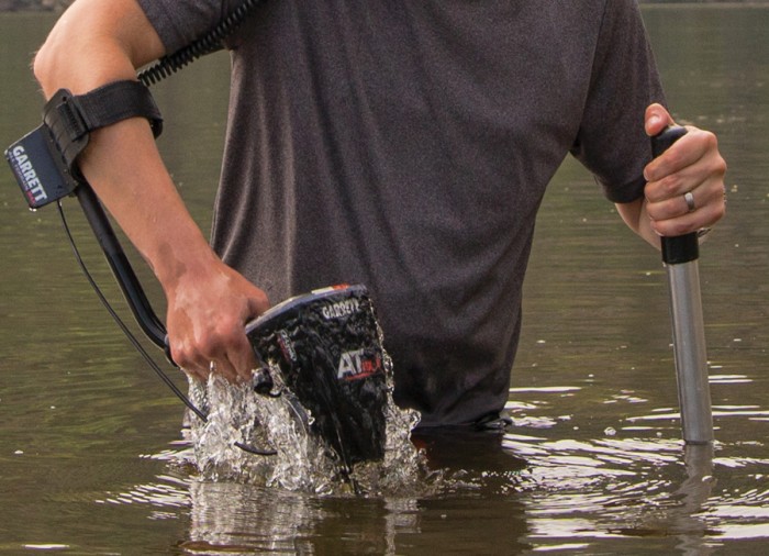 Foto de pessoa dentro da água com um detector Garrett