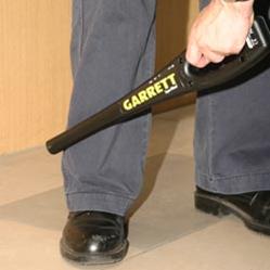 Detector Detector de Metal Portátil Garrett SUPERWAND revistando a perna de uma pessoa