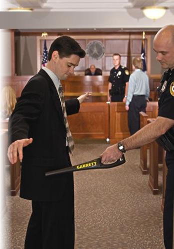 Foto Detector de Metal Portátil Garrett SUPERWAND revistando uma pessoa no tribunal